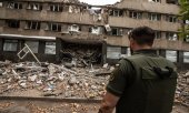 A Ukrainian soldier stands in front of a destroyed building in Mykolaiv on 17 July. (© picture alliance/ZUMAPRESS.com/Hector Adolfo Quintanar Perez)