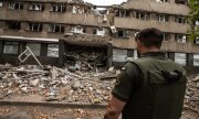 A Ukrainian soldier stands in front of a destroyed building in Mykolaiv on 17 July. (© picture alliance/ZUMAPRESS.com/Hector Adolfo Quintanar Perez)