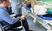 Alexander Nemov (in wheelchair) and Yelena Milashina (lying) at a hospital in Grozny on 4 July. (© picture alliance/dpa/TASS / Sergei Babinets)